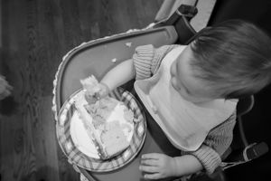 Bird's eye view of a person looking down at a decorated layer cake on a black and white wooden table.