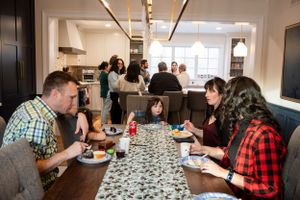 People gather around a long table with a patterned runner for a casual dining experience.