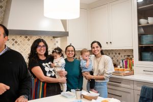 A group gathers in a modern white kitchen during a casual gathering.
