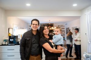 People gather in a modern white kitchen with recessed lighting during a social gathering.