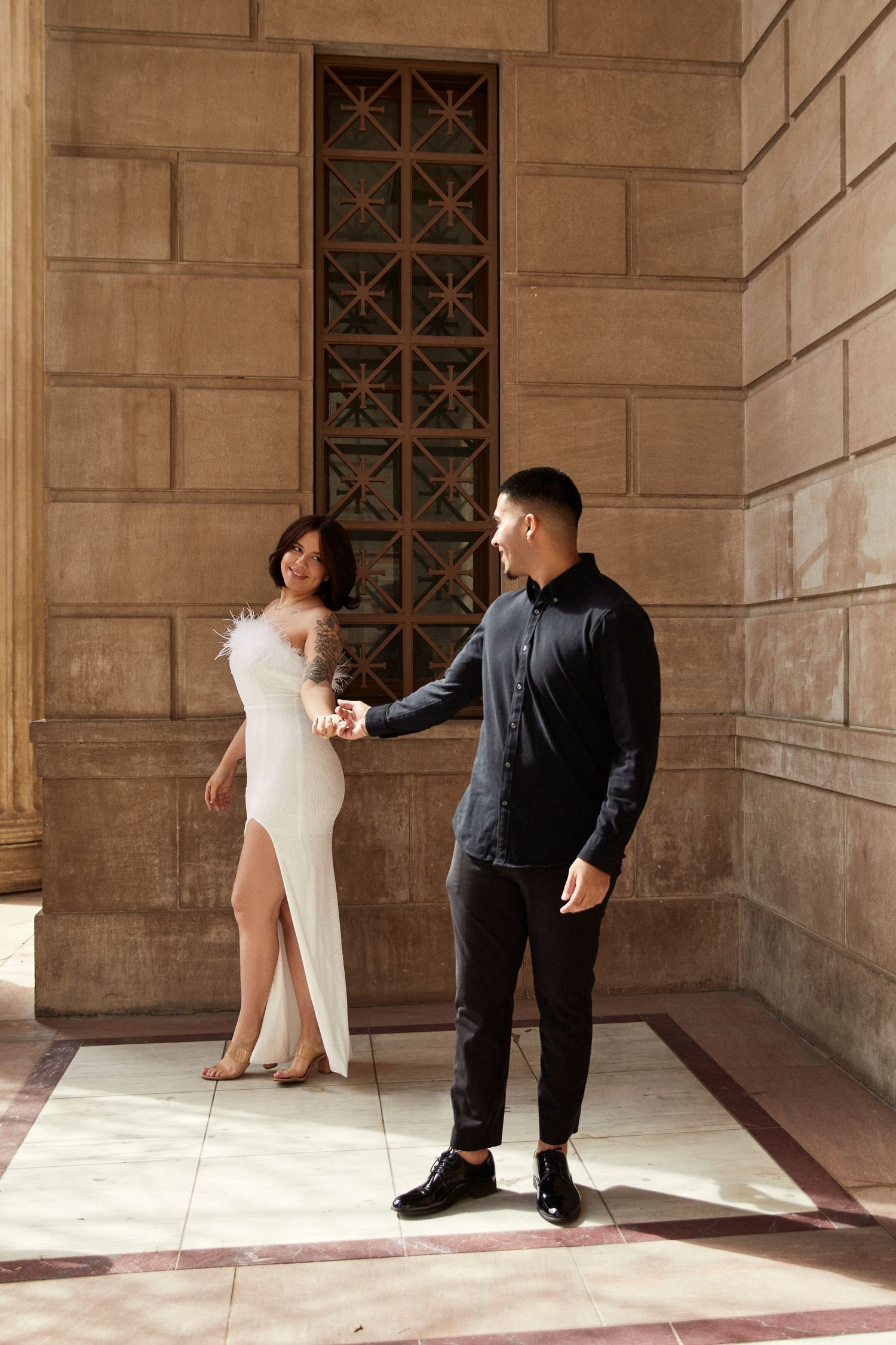 Playful silhouettes of a couple dancing together in an elegant architectural setting.