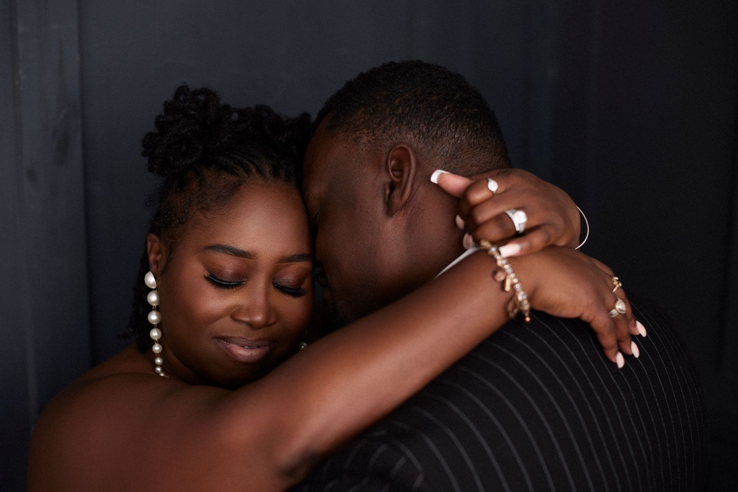 Intimate couple portrait in dark studio with dramatic lighting.