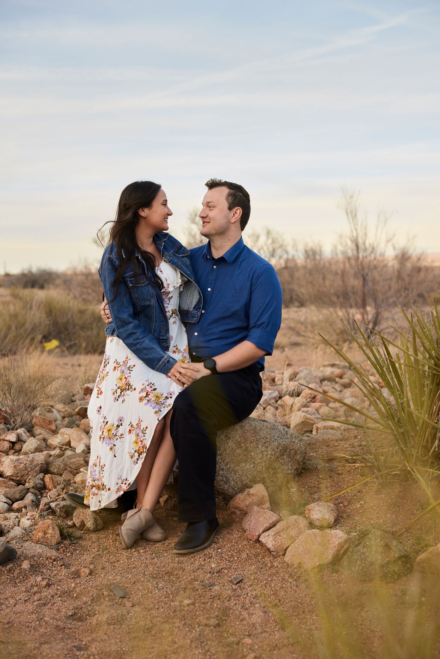 Happy couple laughing together while sitting on rocky desert terrain.