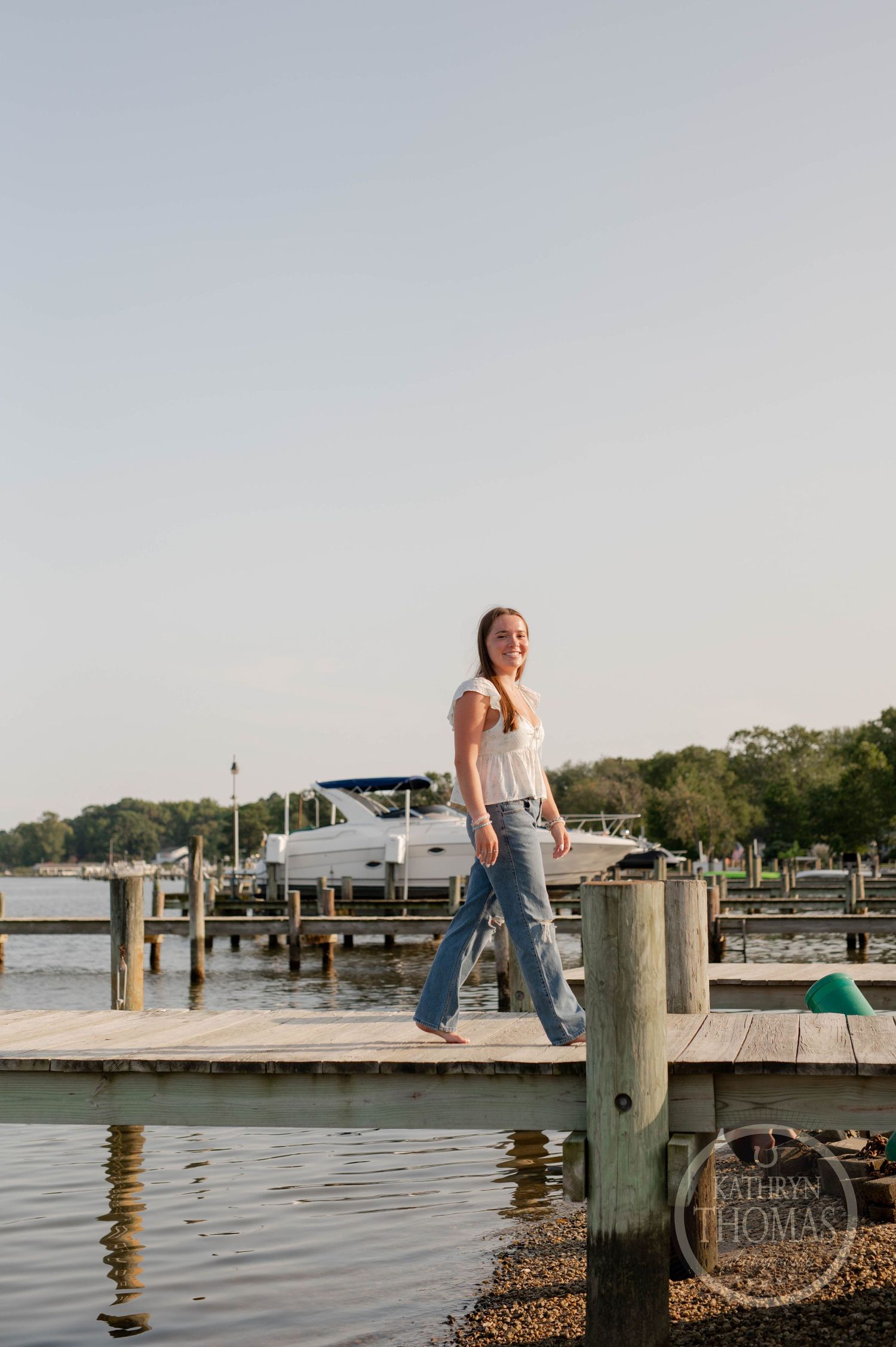 Casual summer portrait on a waterfront dock with boats and pilings in the background.