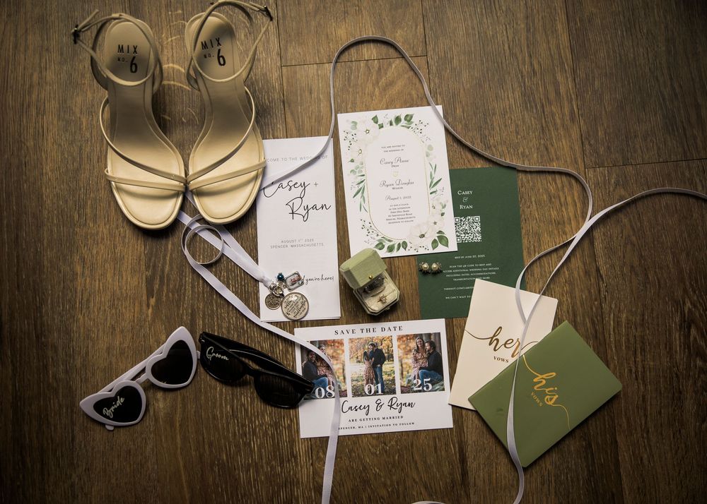 Wedding invitation suite with sandals, sunglasses, and invitation cards styled on a wooden surface.