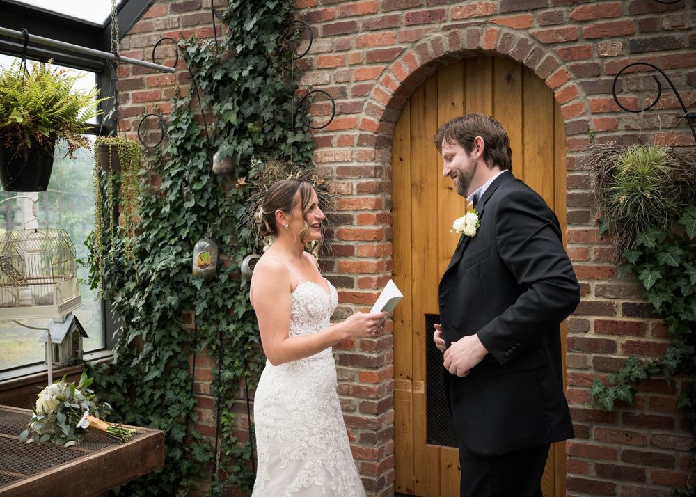 A wedding couple shares intimate moments against a rustic brick wall backdrop with ivy and an arched wooden door.