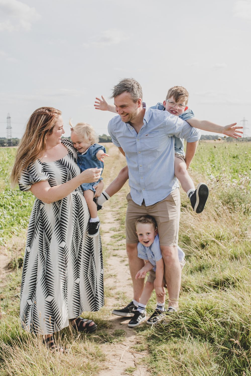 Family enjoying playful moments together on a dirt path through a summer field.
Suffolk Family photos. Beckie Egan Photography.