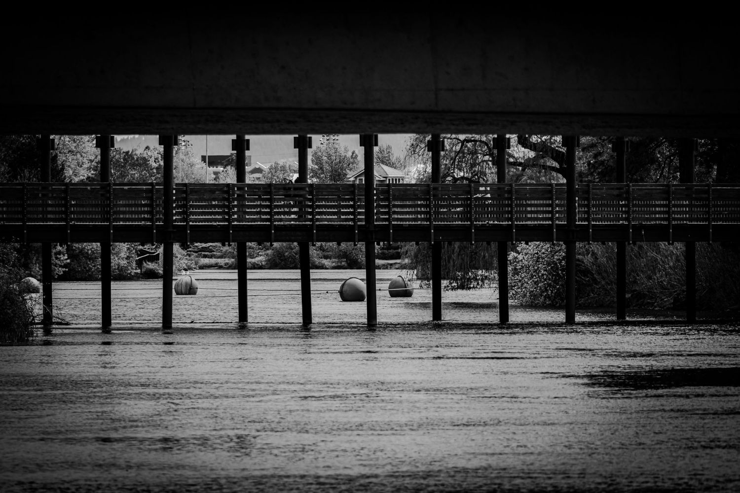 A black and white panoramic sequence showing a person walking across a bridge with repeating architectural elements.