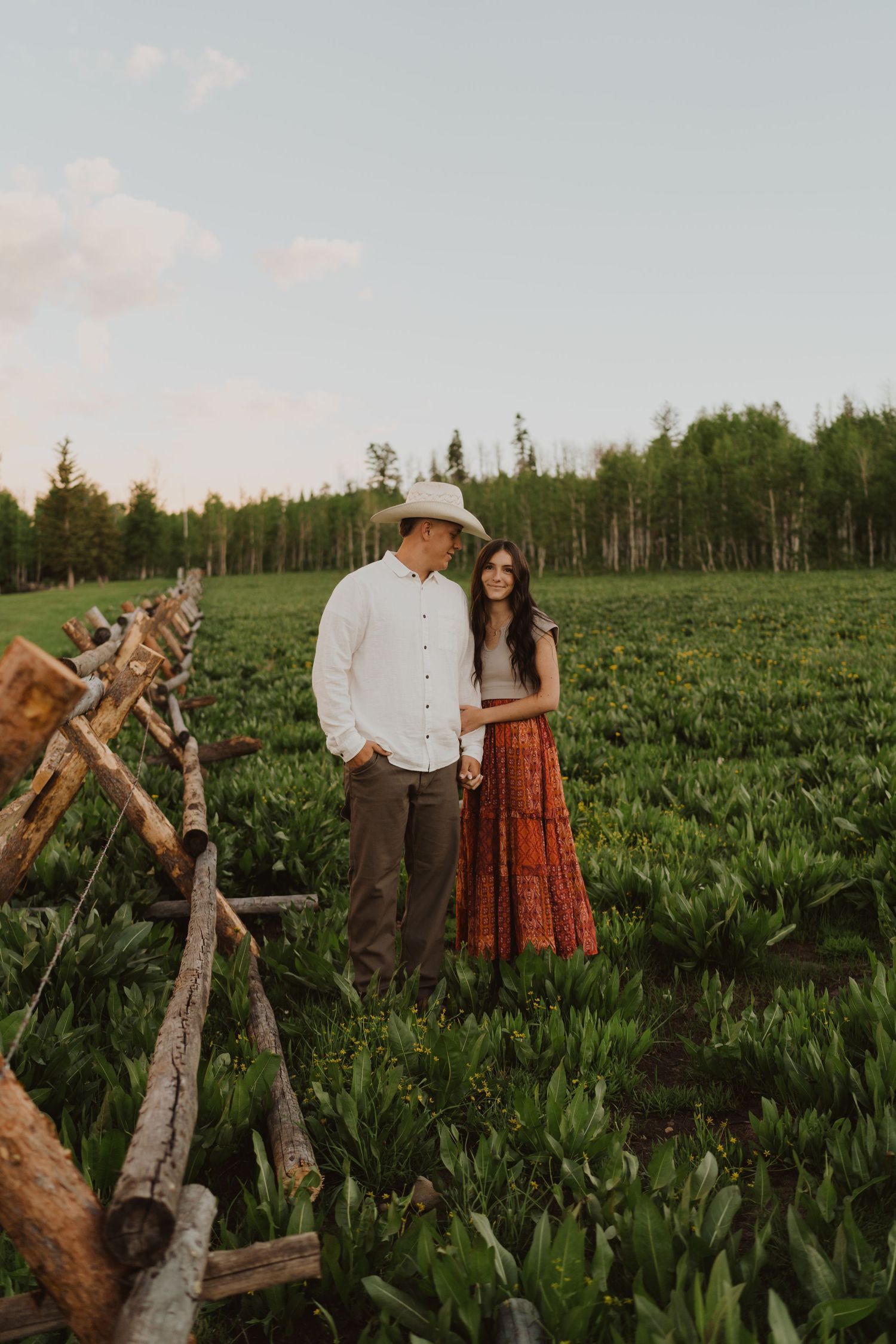 Romantic couple posing in a lush green agricultural field at sunset.