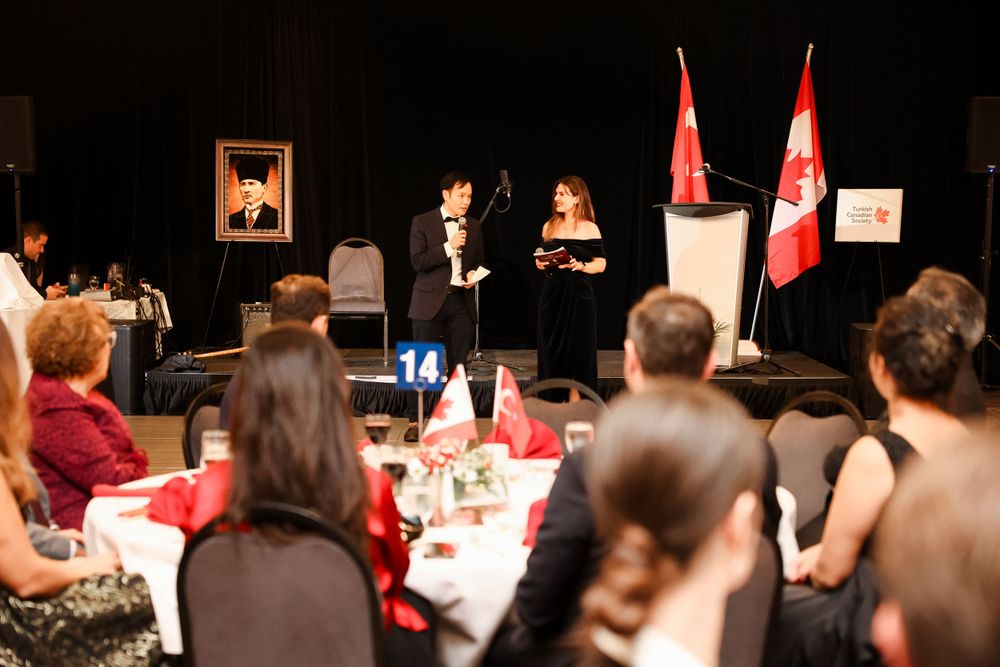 Formal presentation at a Turkish-Canadian event with national flags and podium setup.