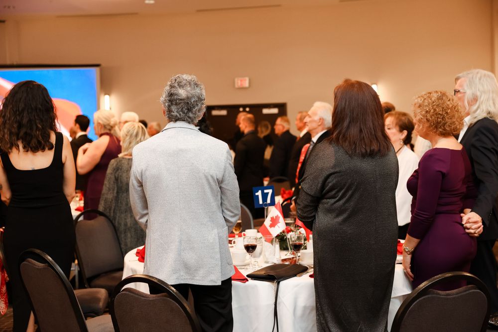Crowd of attendees standing at formal dinner tables during cultural celebration event.