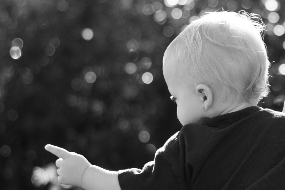 Black and white silhouette of a small child pointing against a bokeh background.