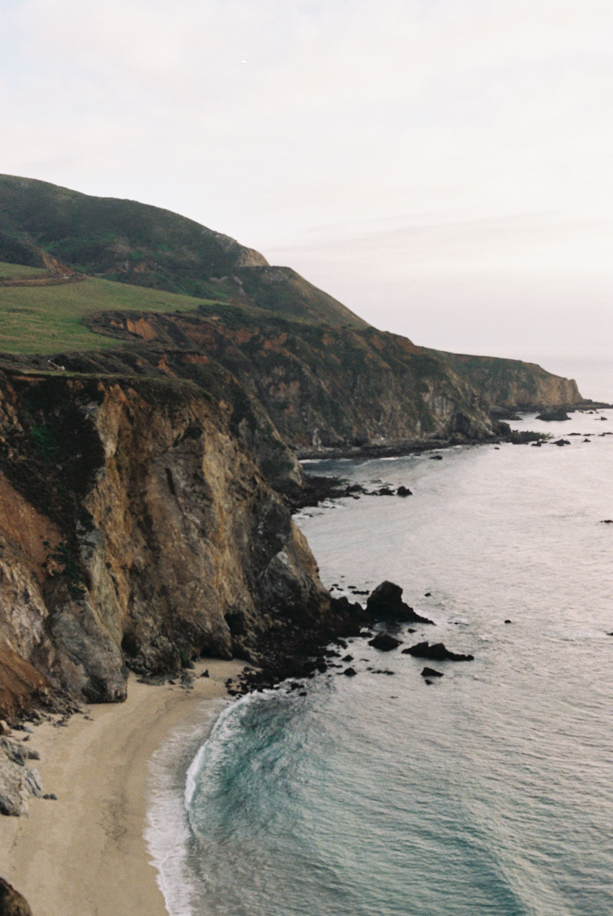 Dramatic coastal cliffs overlooking secluded beach along California's Big Sur coastline.