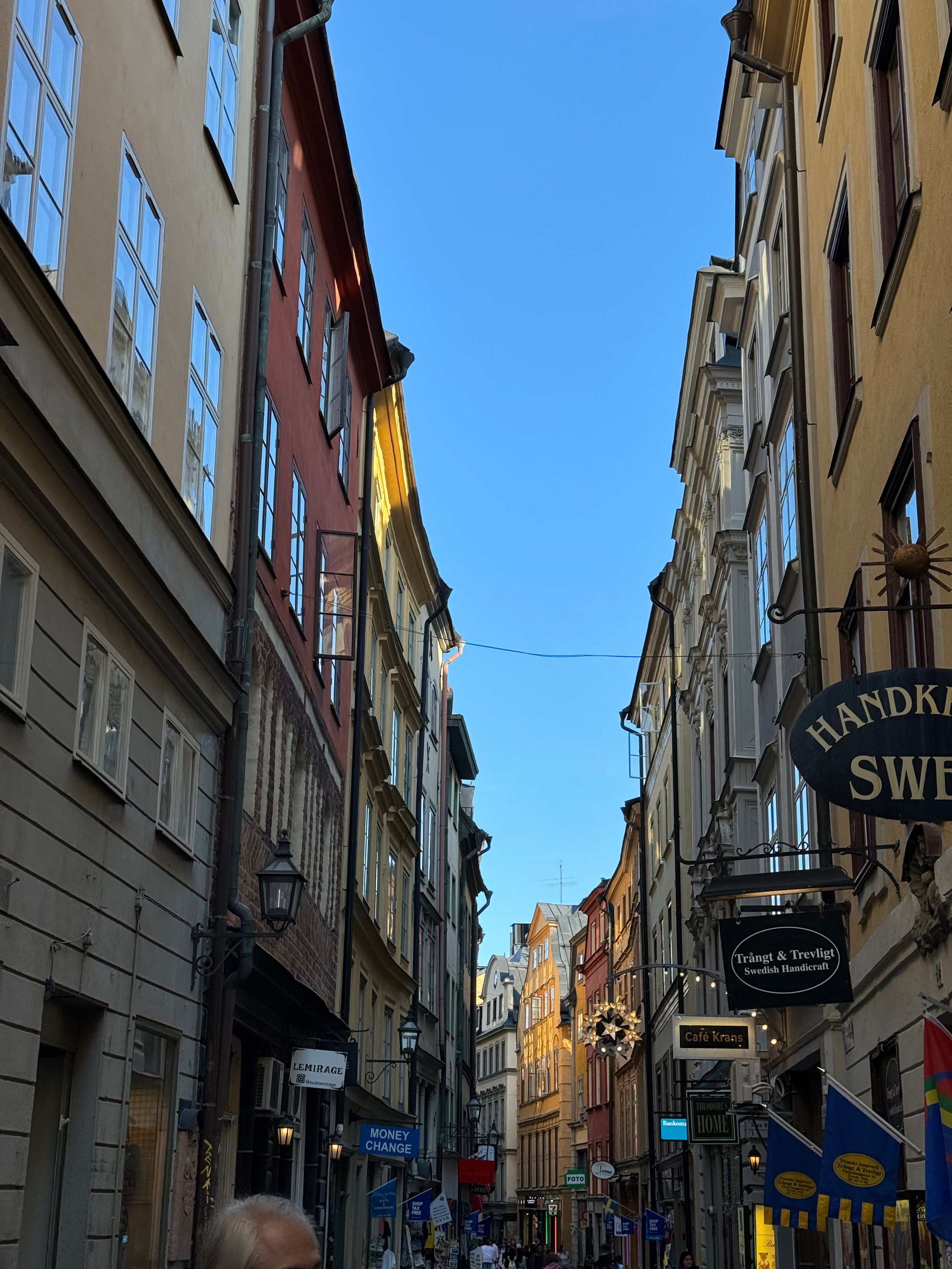 Narrow cobblestone street lined with colorful historic buildings in a European city center.