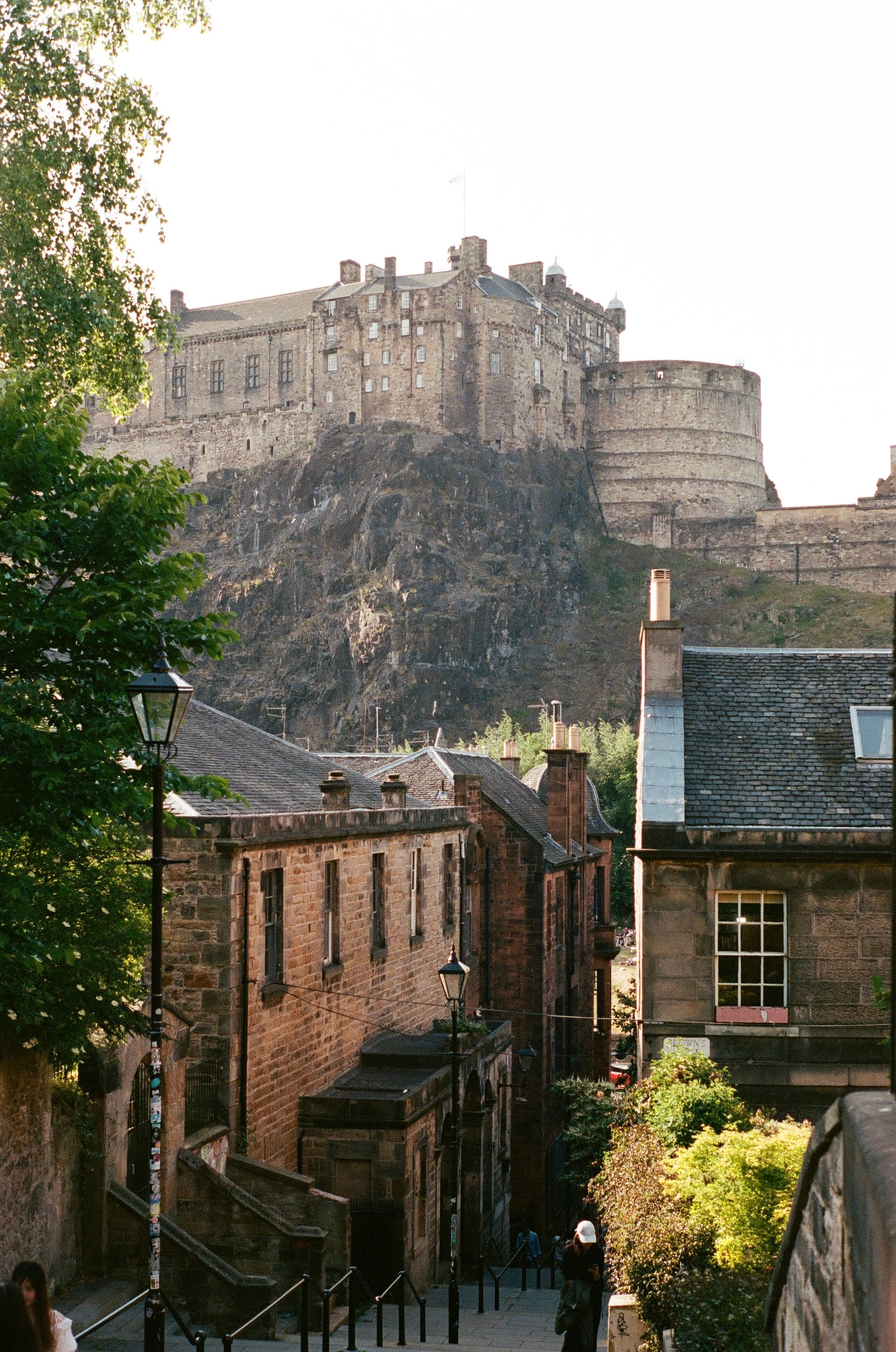 Edinburgh Castle towers above historic buildings along a steep cobblestone street.