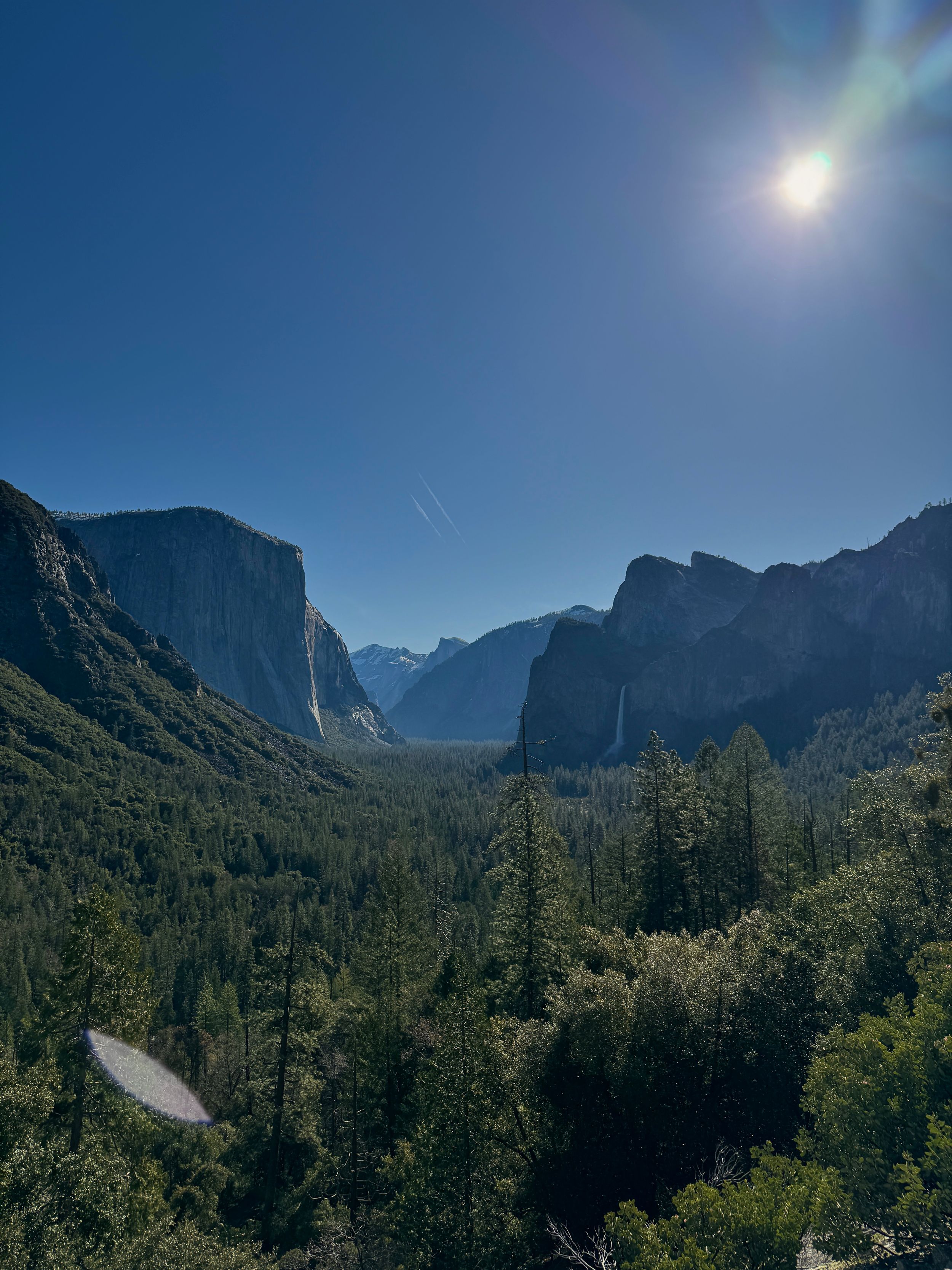 Stunning view of Yosemite Valley with El Capitan and Half Dome under bright sunlight.