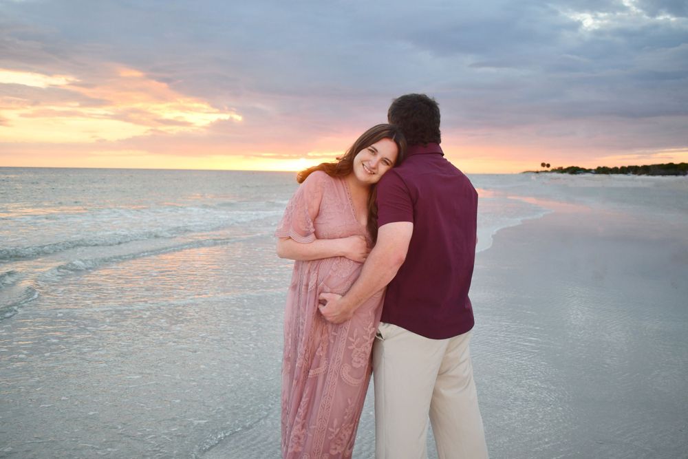 Breathtaking golden and pink sunset on the beach with a maternity couple captured by LMQ Photography