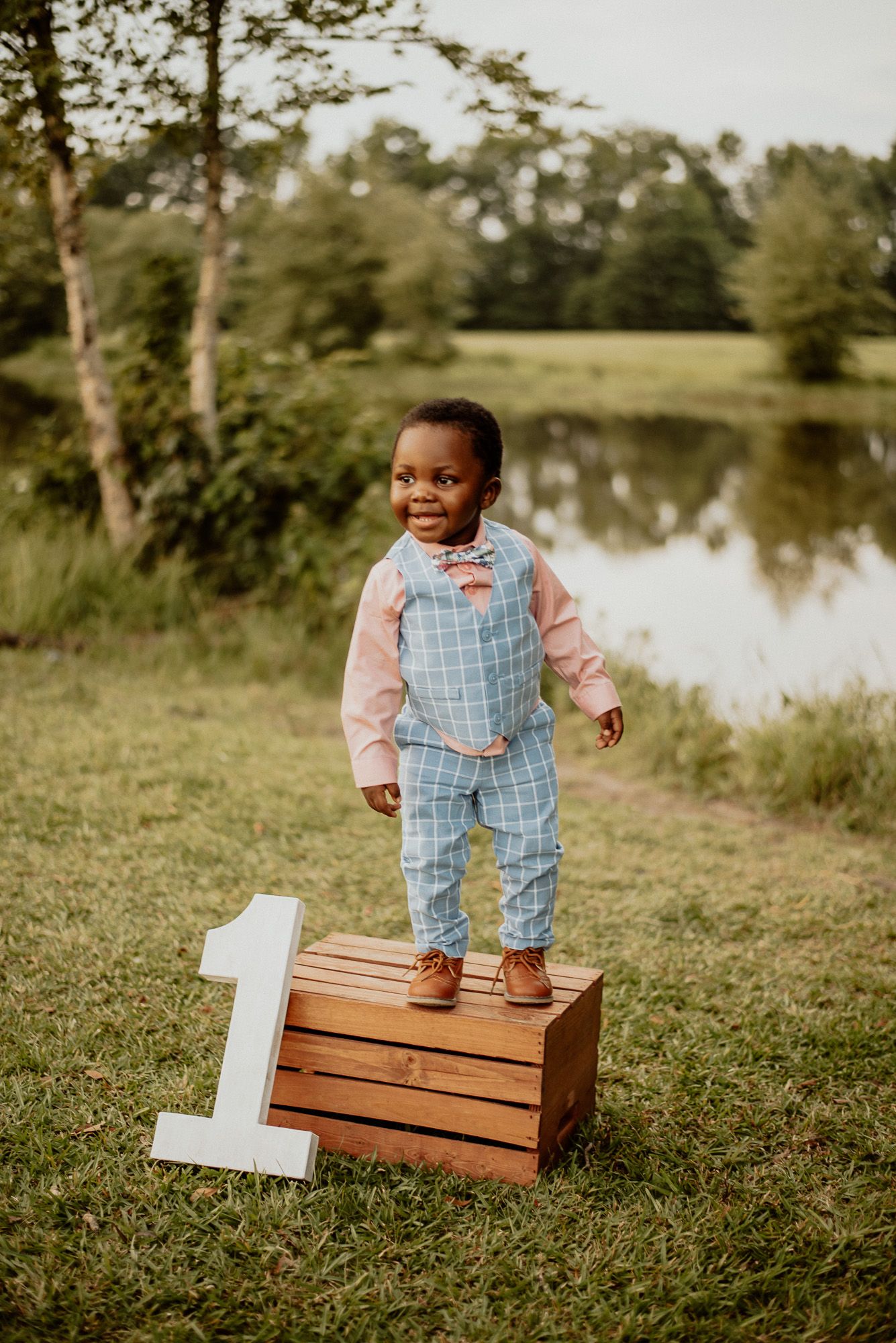 A one-year birthday celebration setup outdoors with wooden crates and a number one prop.