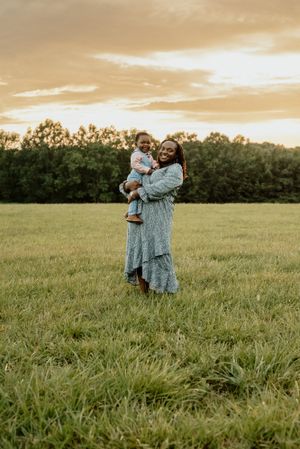 A tender outdoor family moment at sunset in a grassy field with matching blue outfits.