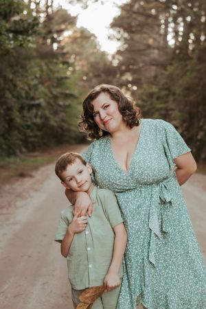 Parent and child share playful moments in matching mint green outfits on dirt path.
