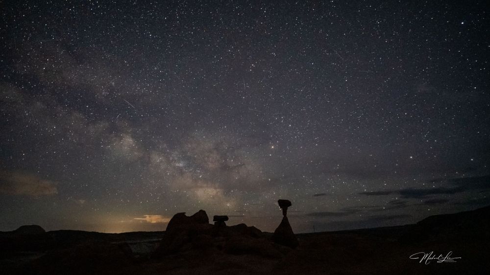 Silhouetted rock formations against a starlit night sky in the desert.