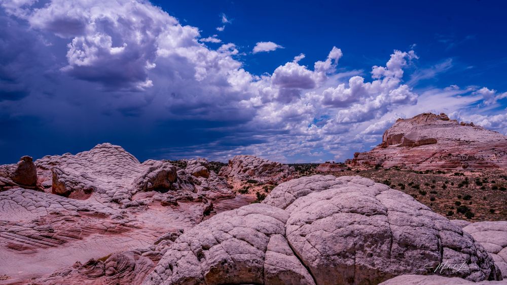 Storm clouds gather over red rock formations in the desert landscape.