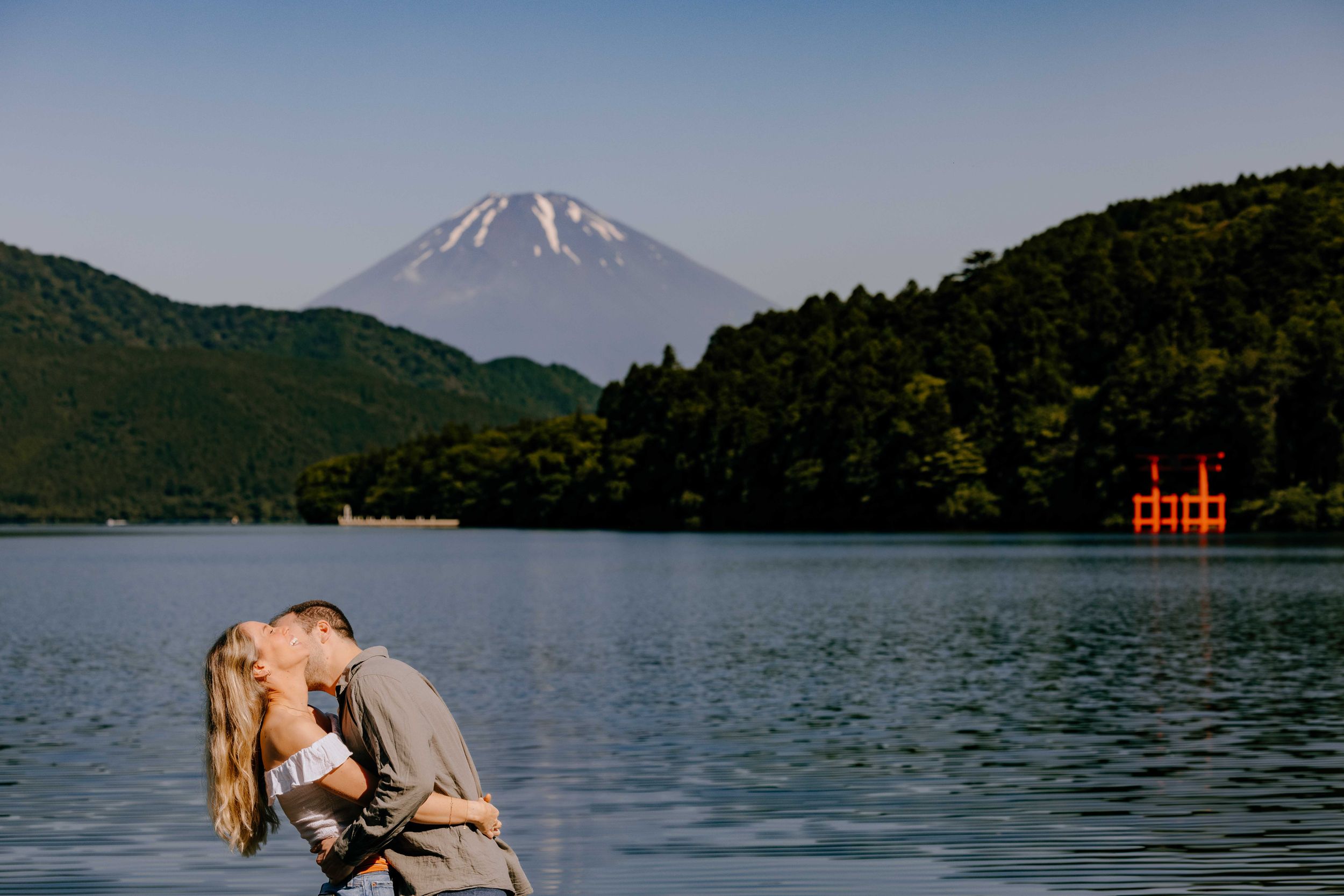 Scenic view of Mount Fuji rising above Lake Hakone with a red torii gate visible in the distance.
