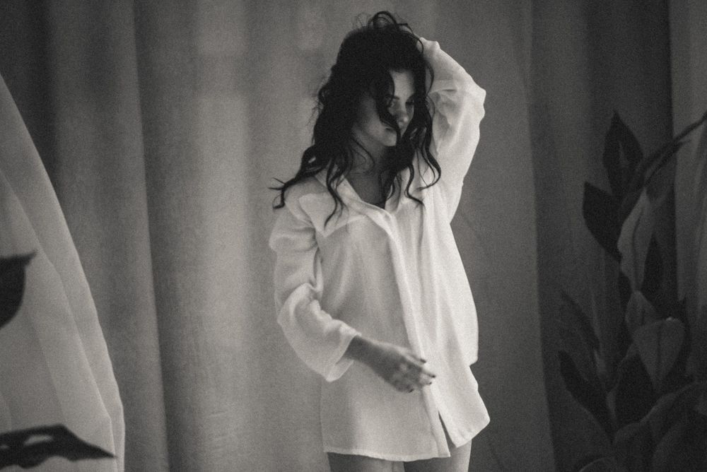Artistic black and white portrait of someone in a white shirt with dramatic lighting.
