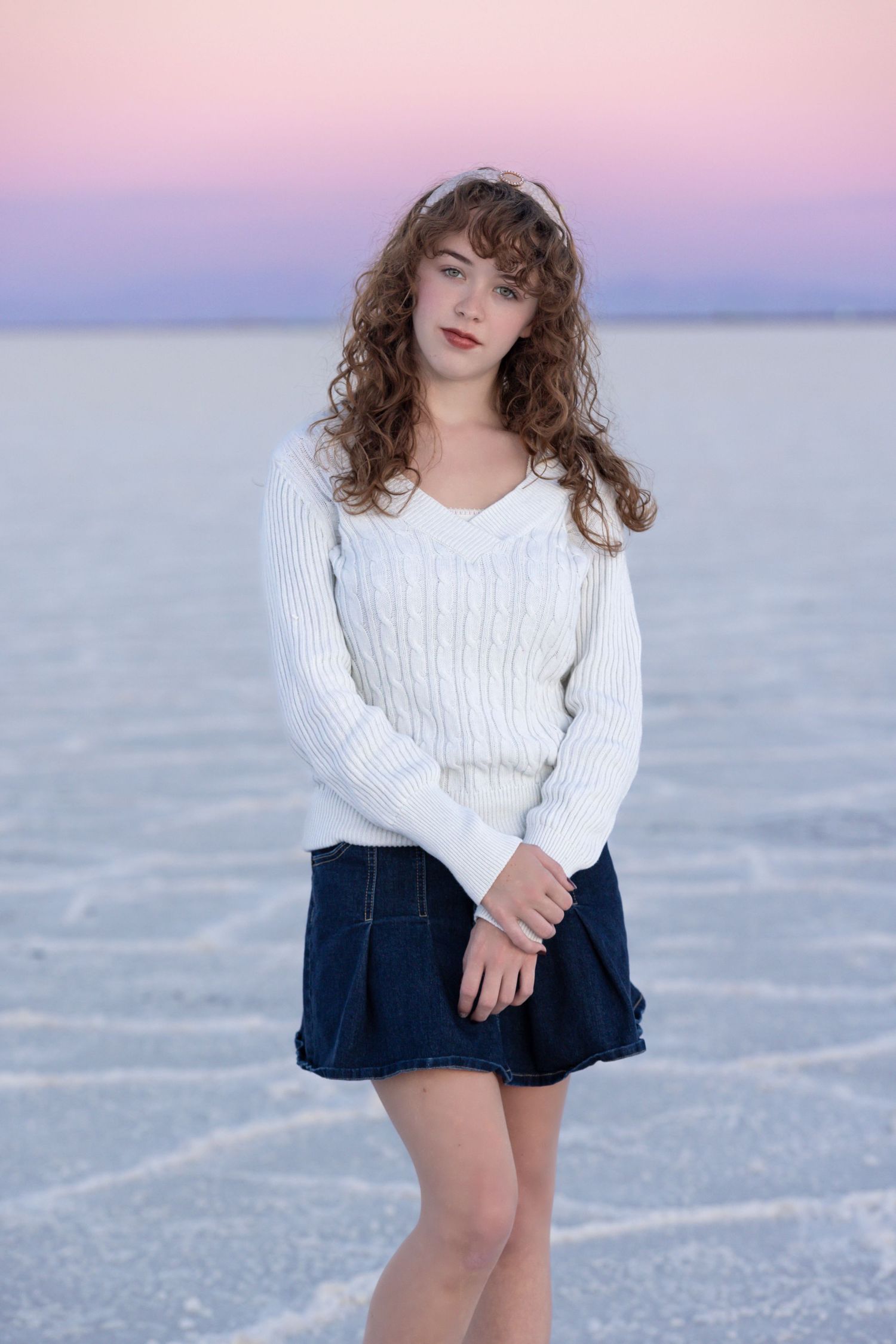 Utah Senior Photographer takes photo of senior for Bonneville salt flats photography at sunset with a pink and purple sky.