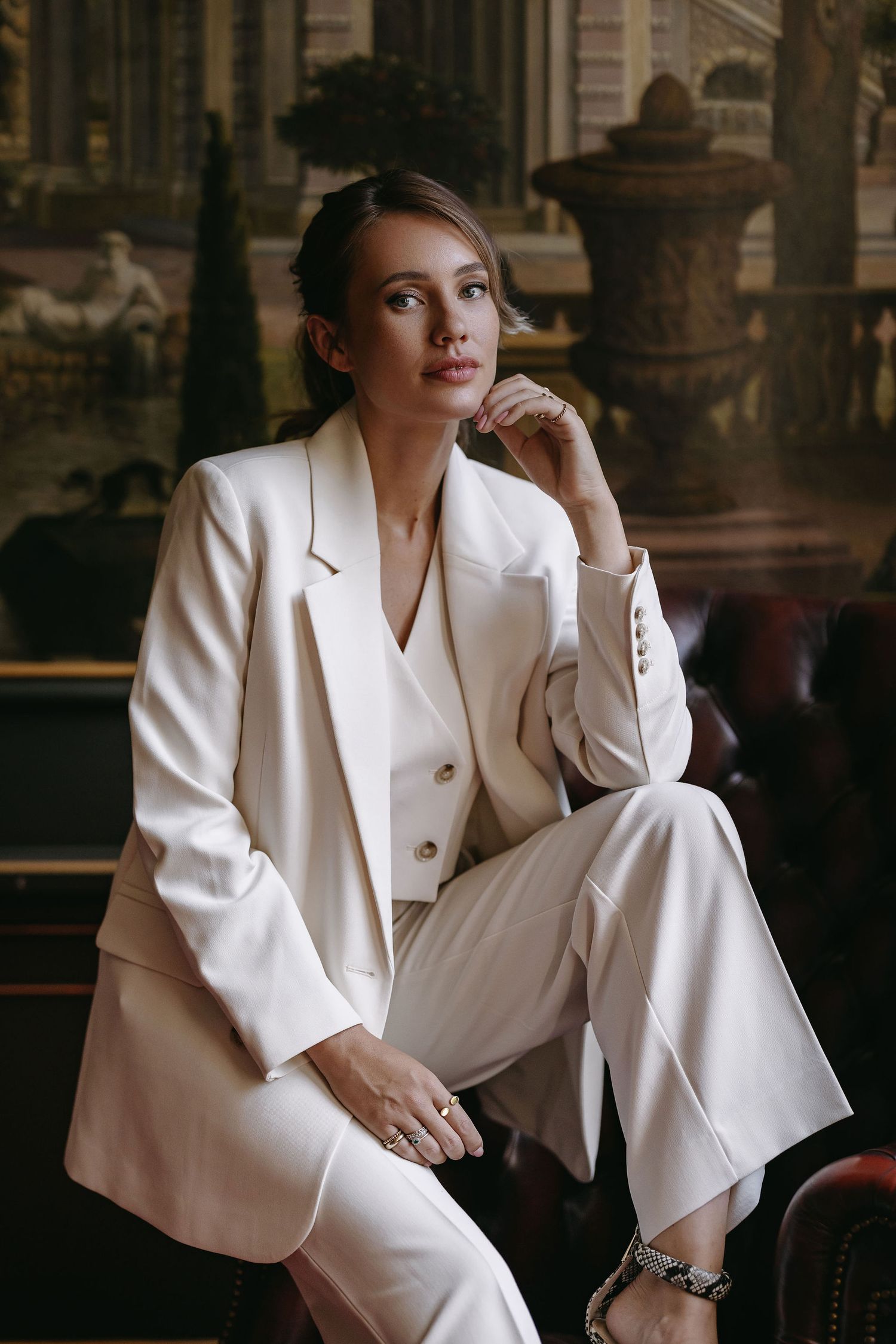 Professional portrait in crisp white suit against elegant backdrop.