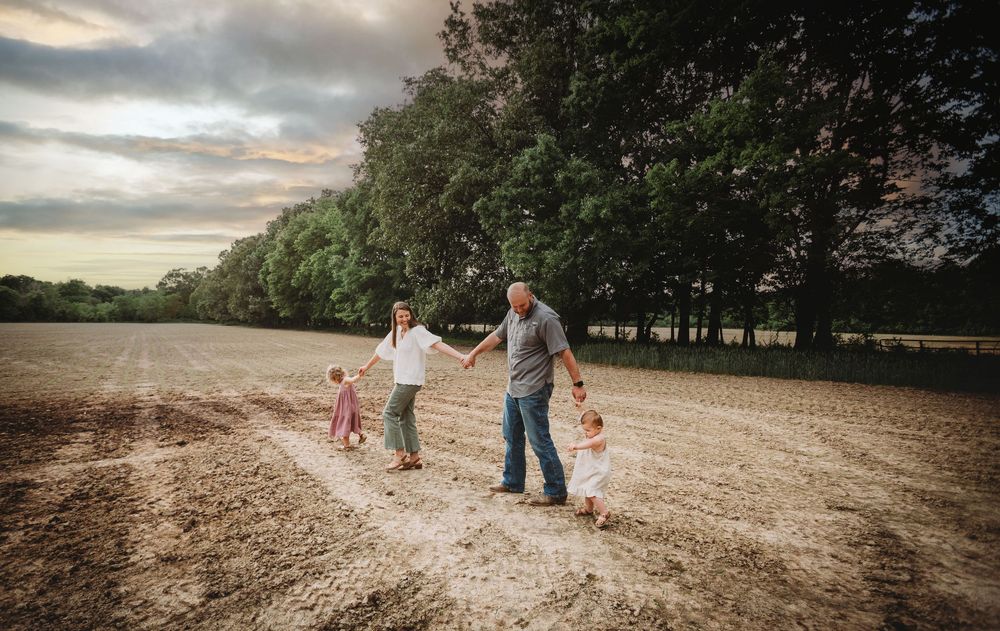 People walk together down a dirt path at sunset with trees lining the background.