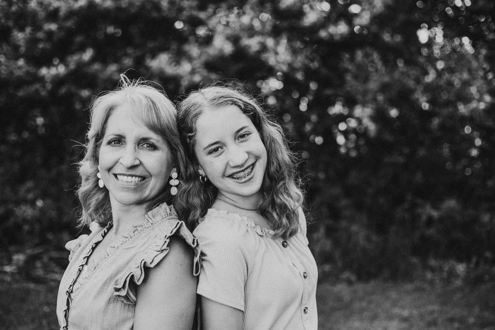 Black and white portrait of two people standing back to back outdoors.