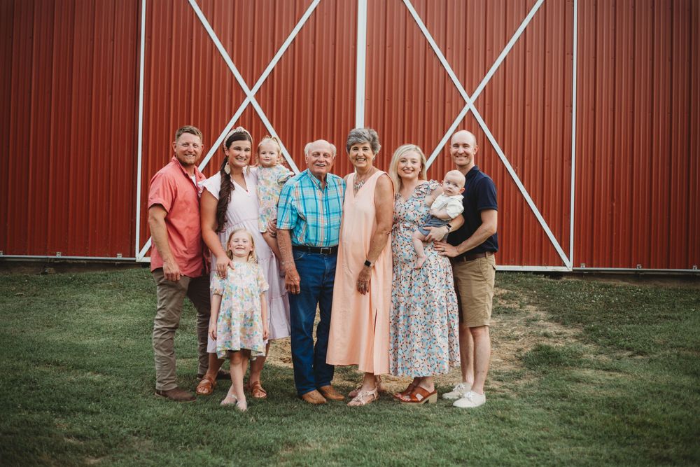 Multi-generational family poses for a group photo in front of a red barn.