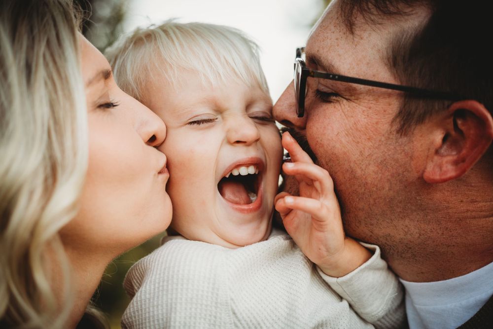 A joyful family moment captured with kisses and laughter in an intimate close-up photograph.