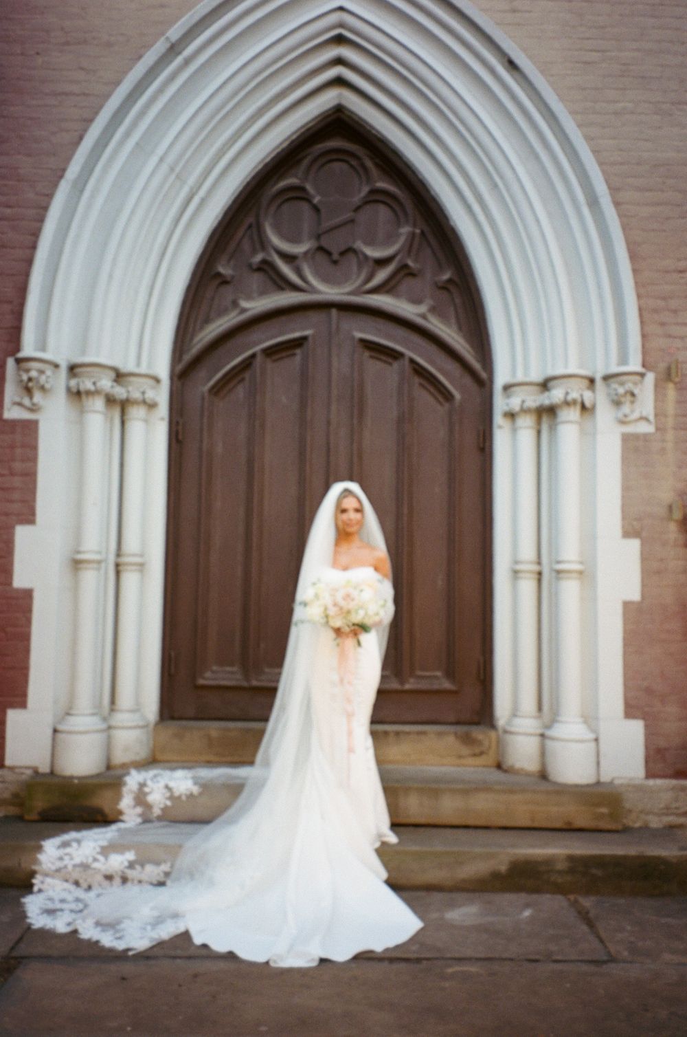 A wedding dress silhouette against a gothic church doorway with ornate architectural details.