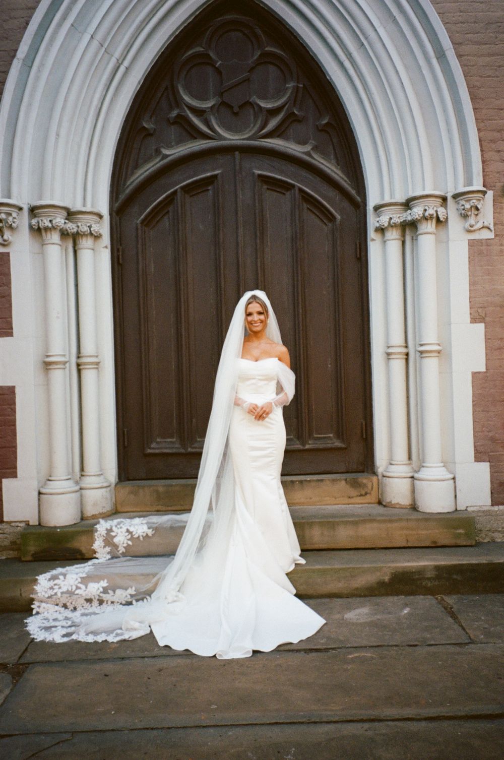 An elegant bridal portrait in front of a wooden church door with gothic archway.