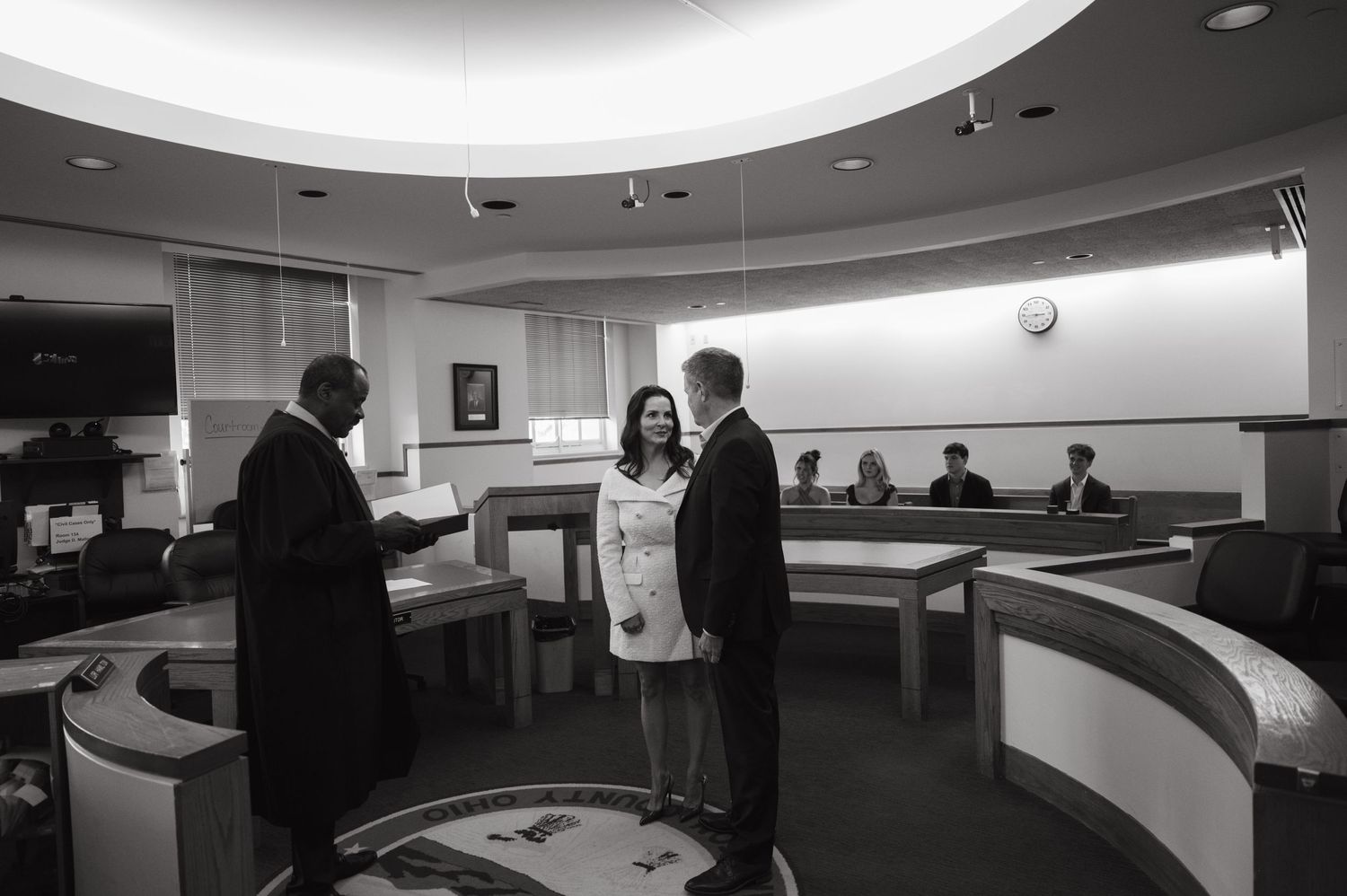 A civil ceremony taking place in a formal office setting with an official presiding.