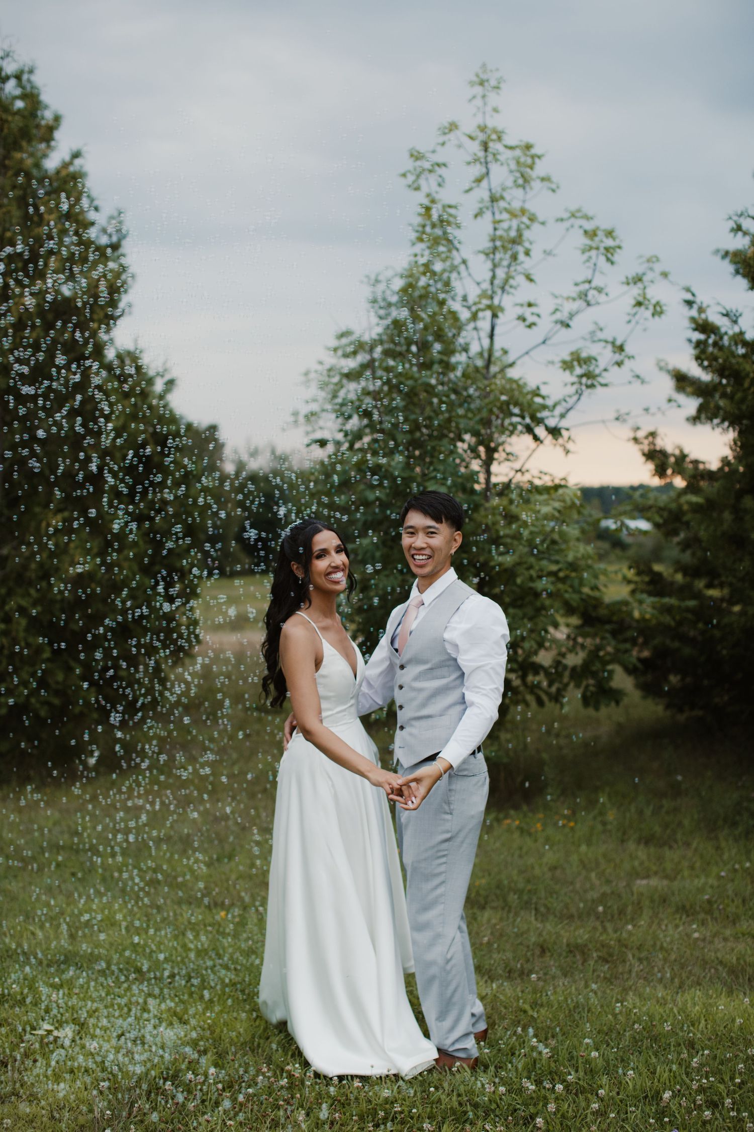 A couple celebrating their wedding day while water sprays around them in a garden setting.