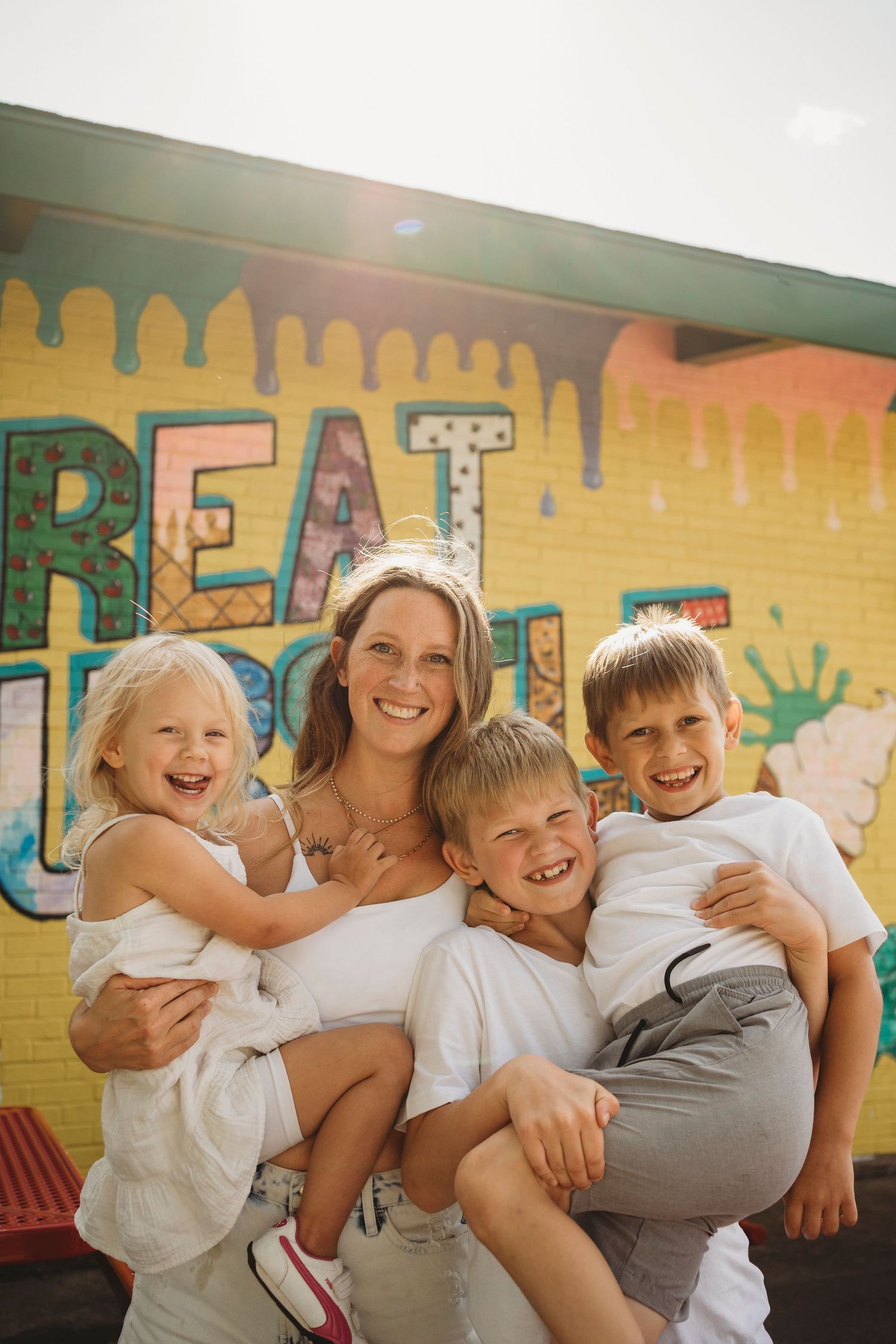Happy group photo against a yellow wall with colorful street art and dripping paint effect.