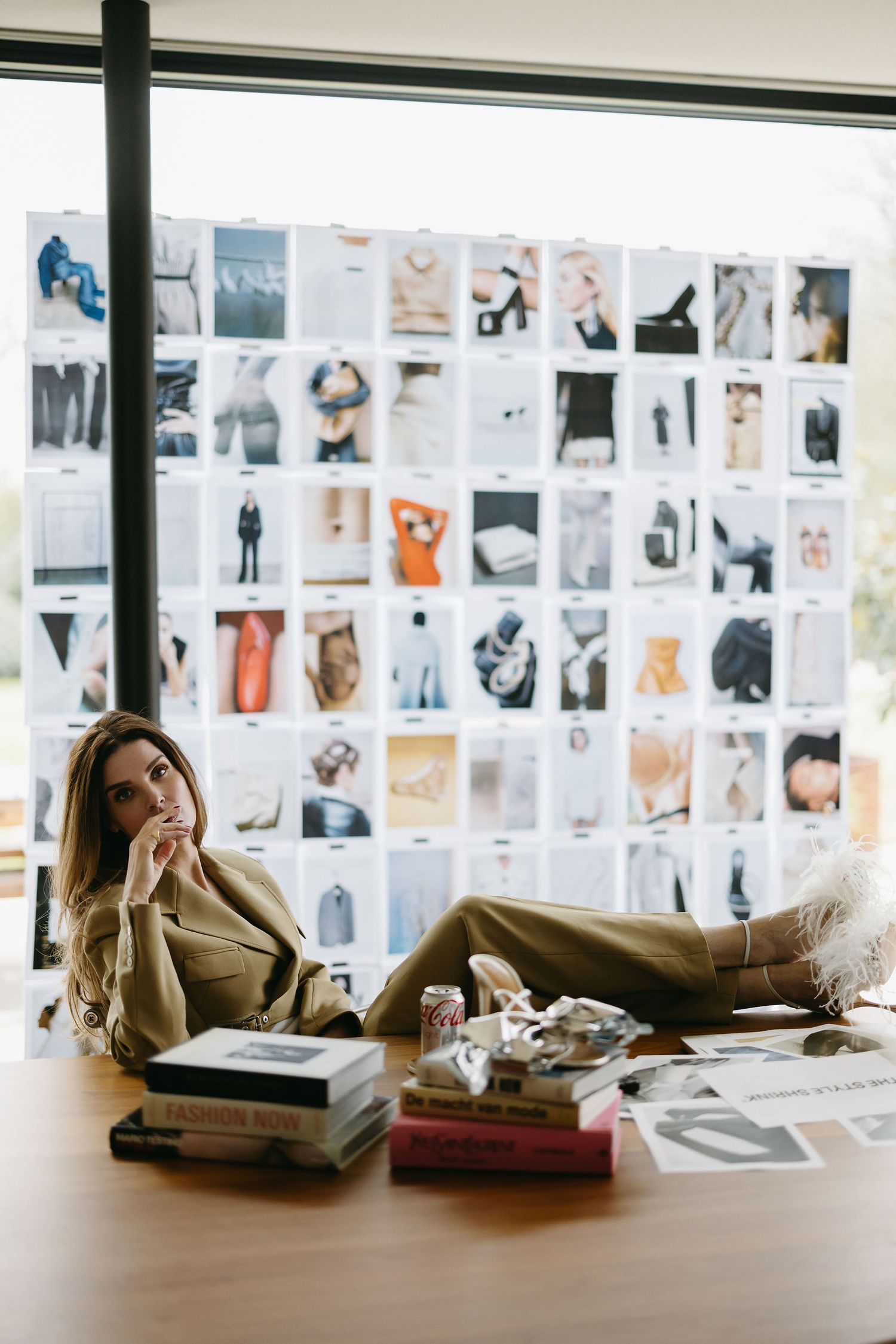 Creative workspace with photo mood board and scattered books showing fashion inspiration.
