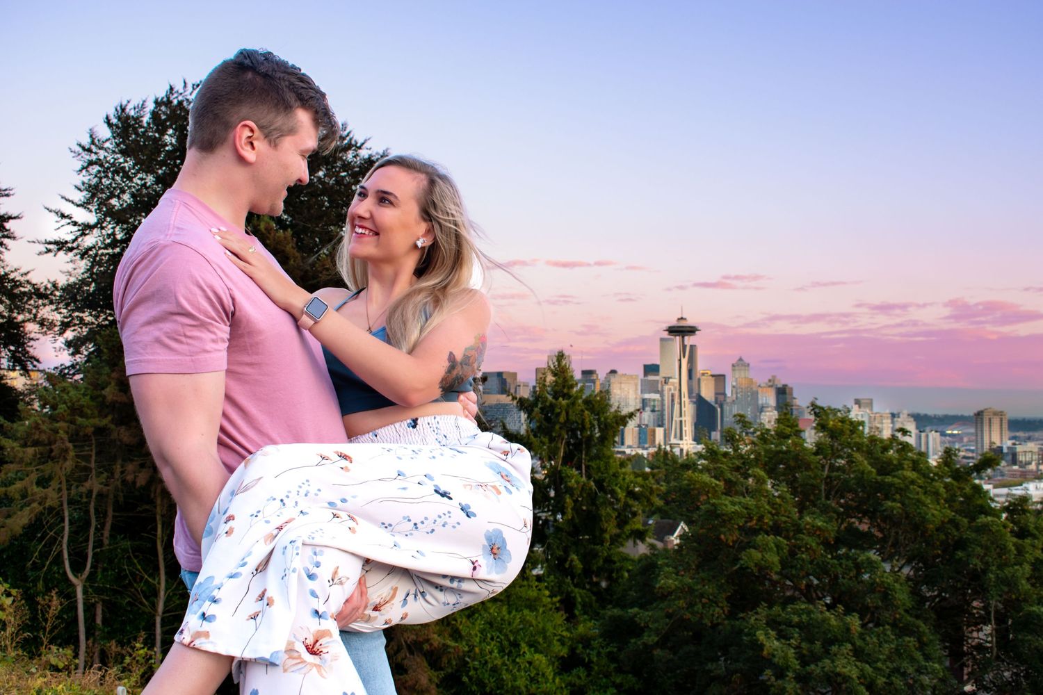 Playful Seattle couple photo with vibrant sunset skies—capture your love story with a scenic urban view of the Space Needle from Kerry Parka
