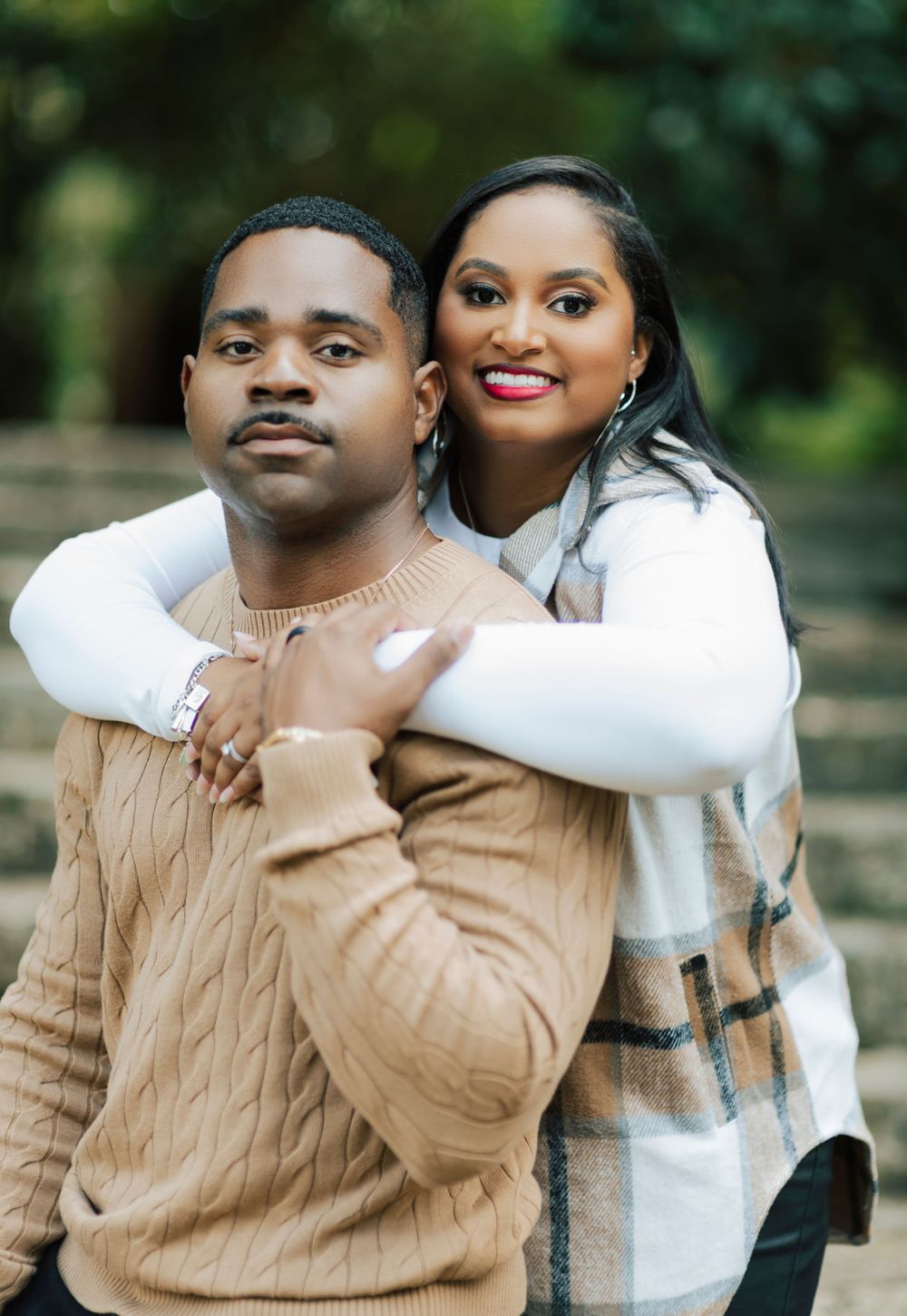 Golden hour engagement photo with soft sunlight through the trees.