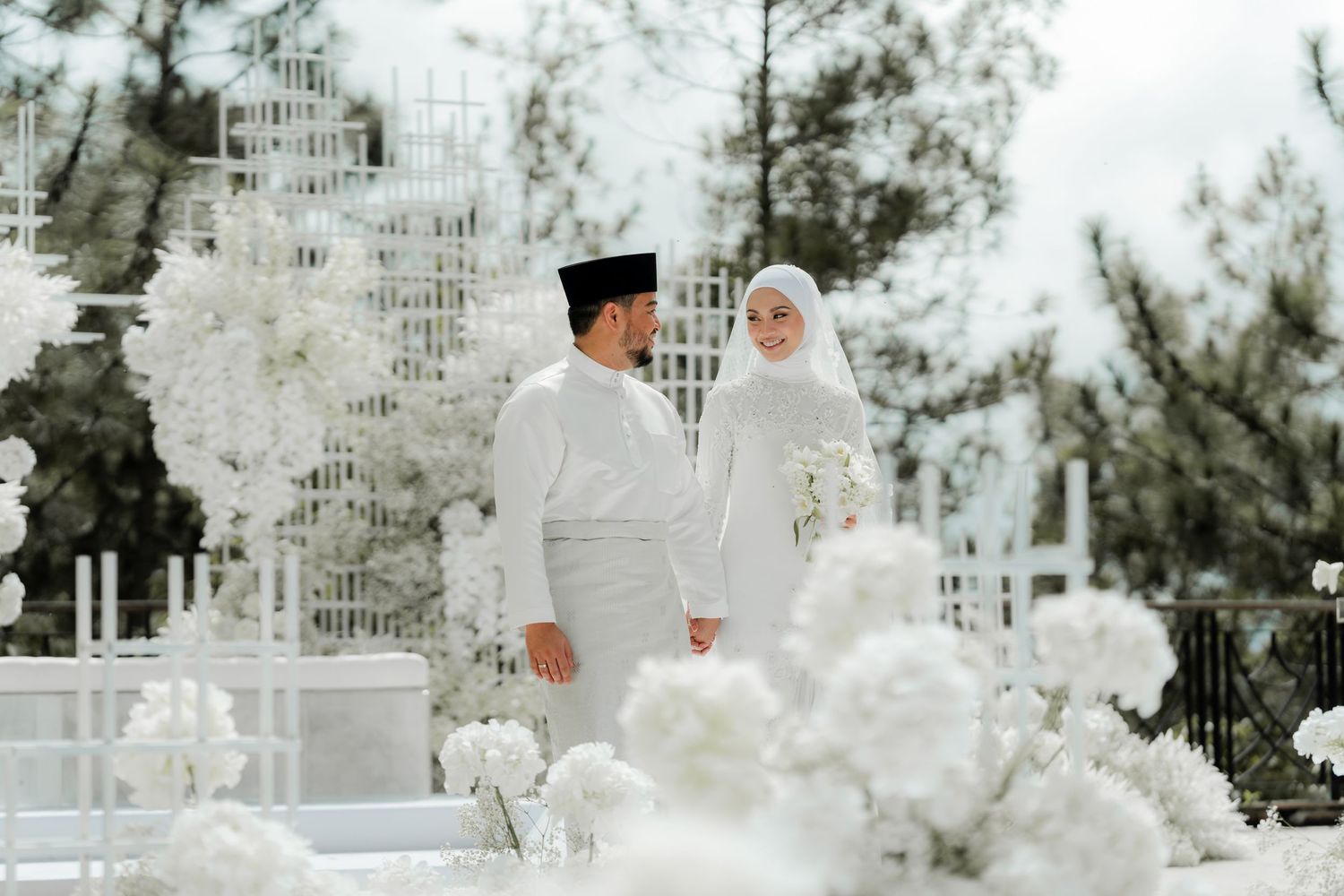A traditional Islamic wedding ceremony with white decor and floral arrangements in an outdoor setting.