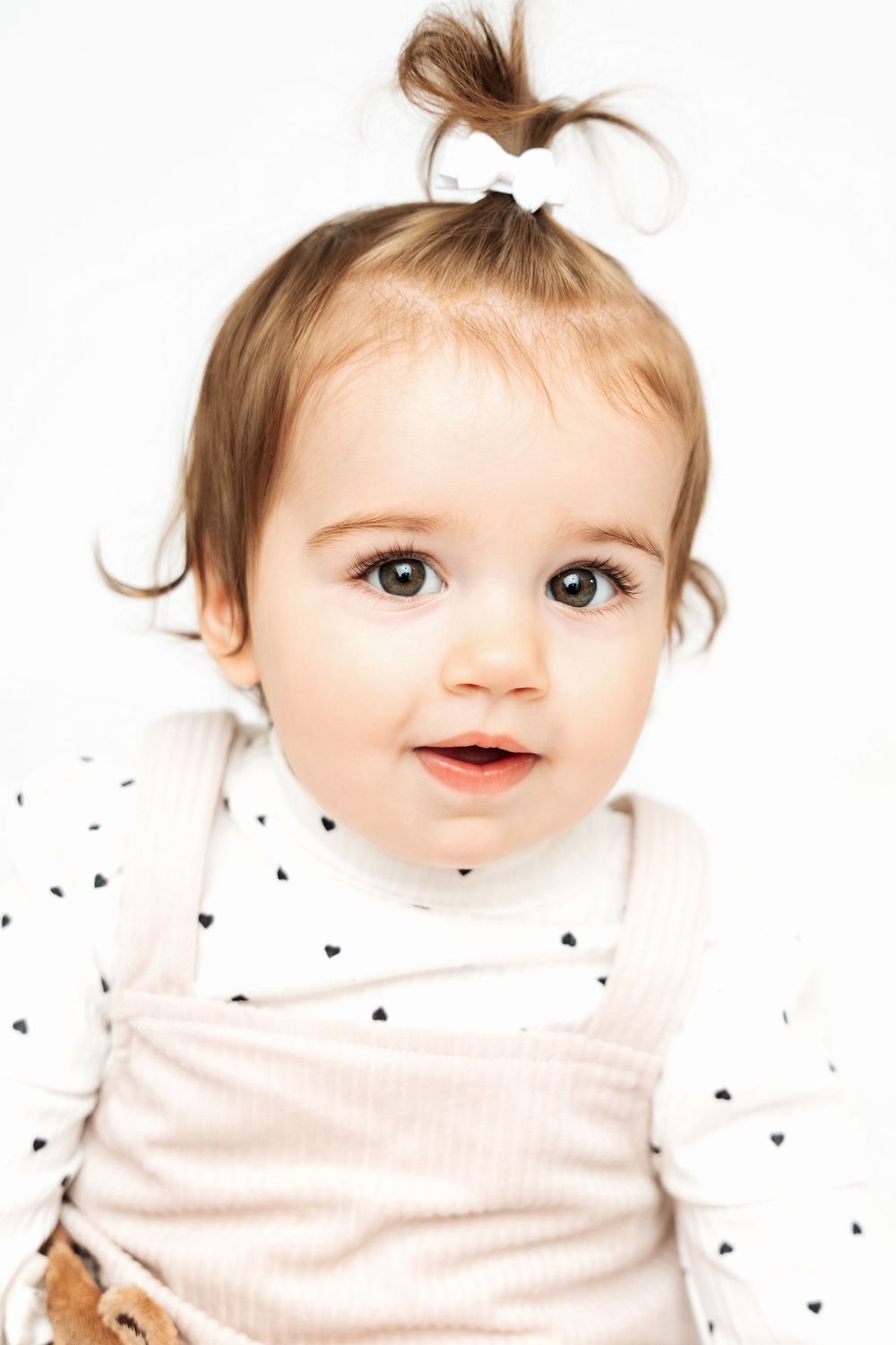 Baby wearing white shirt shows progression of four different facial expressions and emotions.