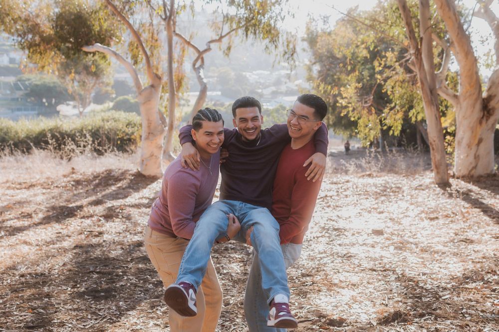 Friends playfully carrying and supporting each other while laughing in a natural outdoor setting.