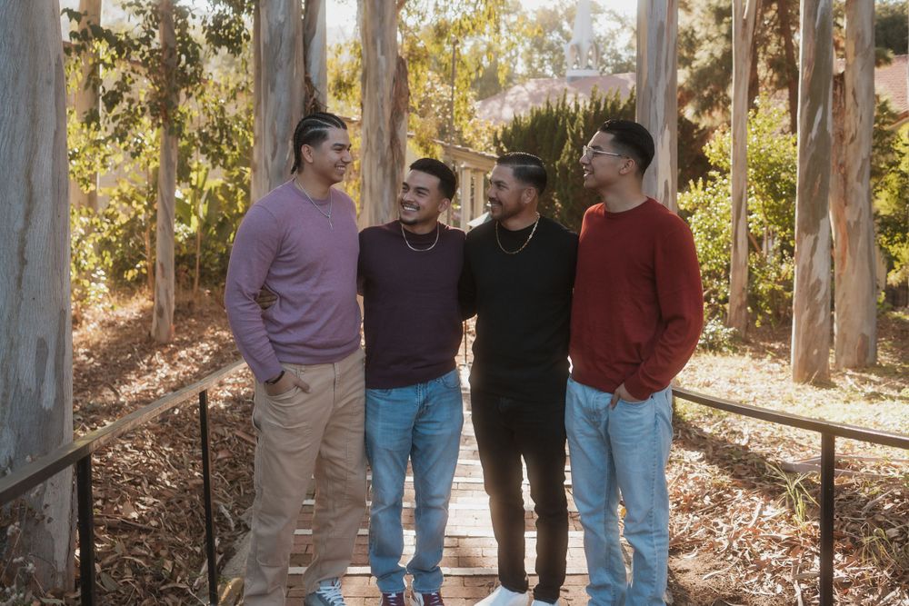 Four people gather for a casual photo in a wooded setting with eucalyptus trees.
