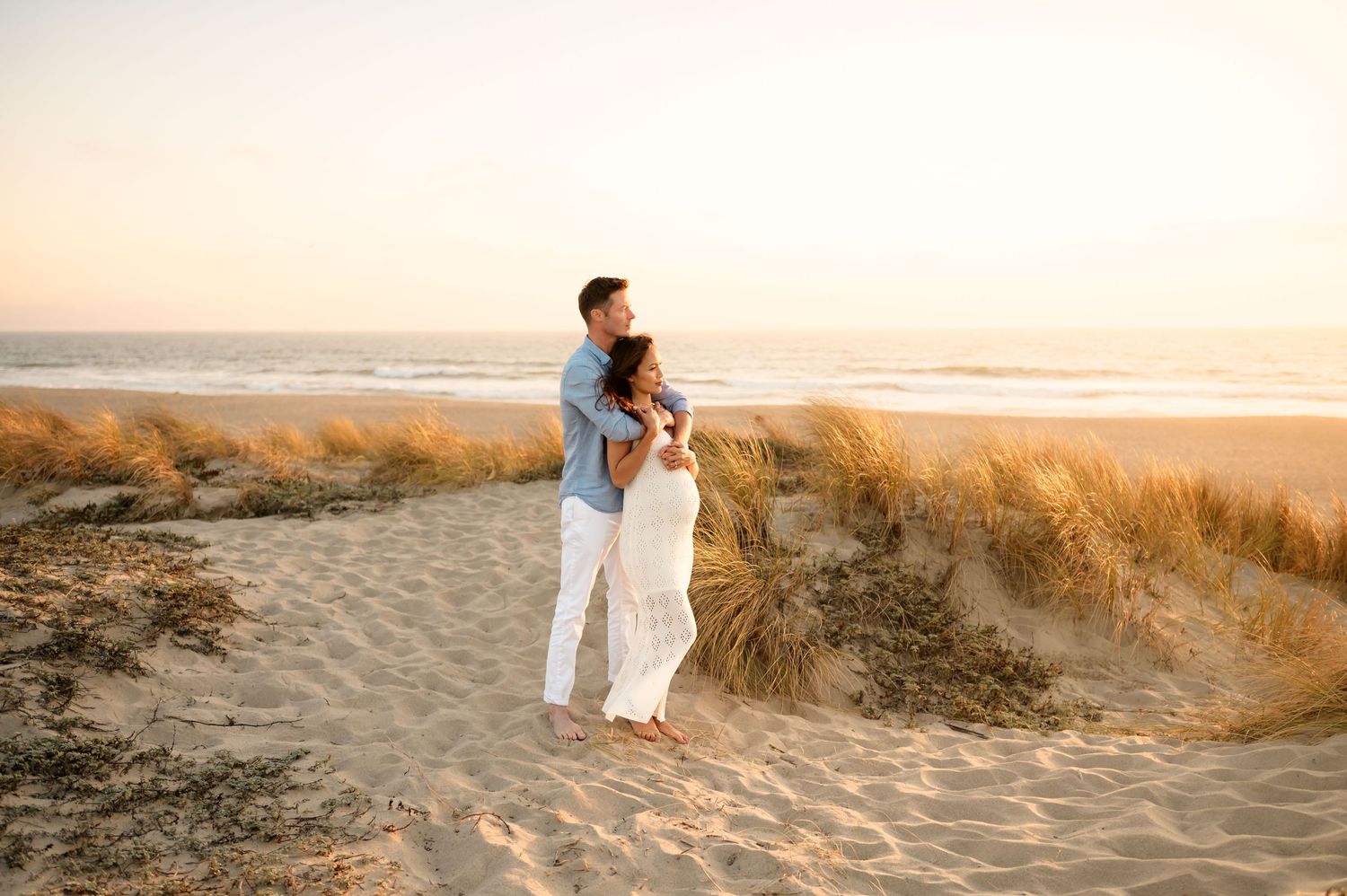Couple standing together on sand dunes during their sunset maternity photos in Ventura, CA by Ojai photographer