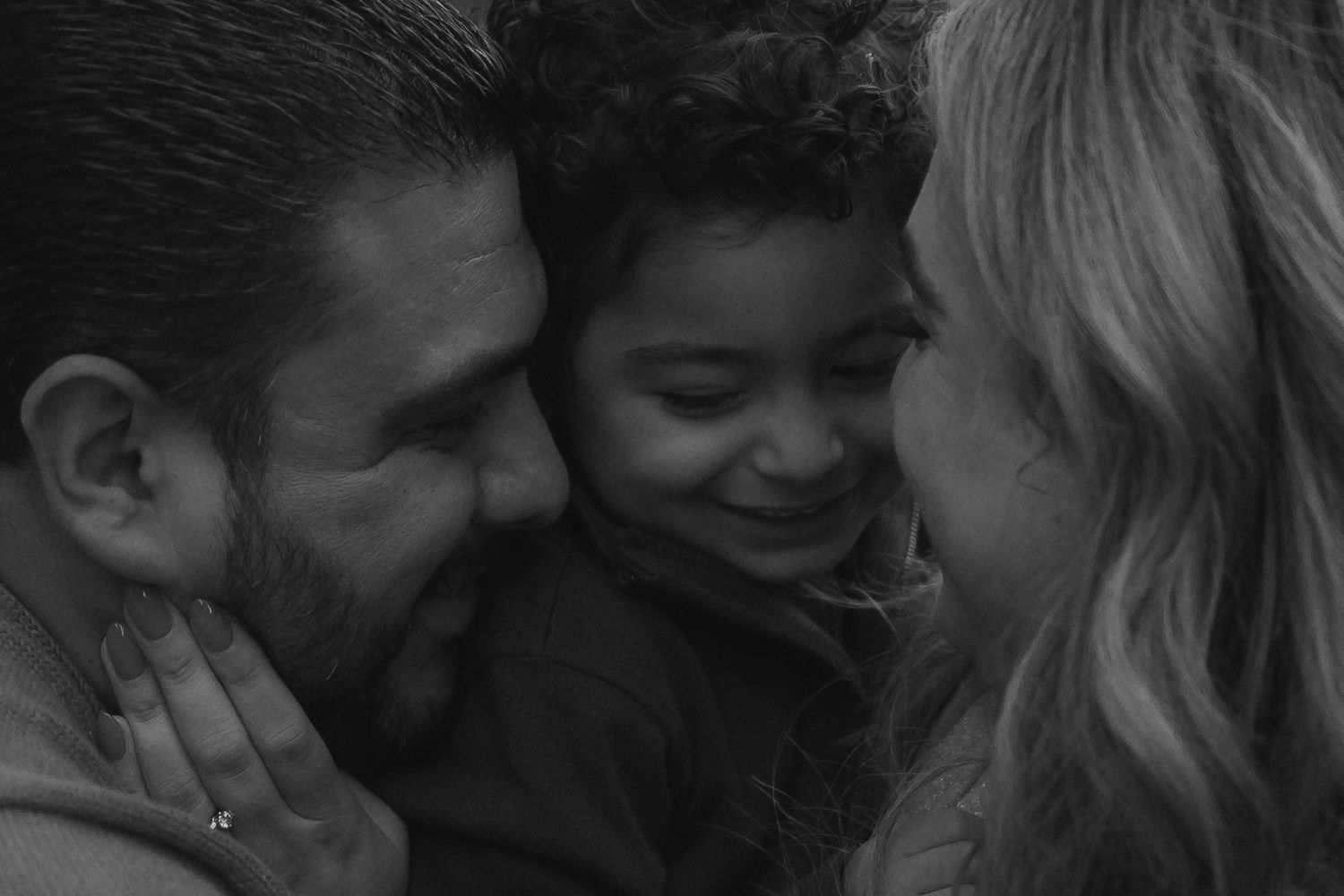 An intimate black and white family portrait capturing a tender moment of connection and joy.