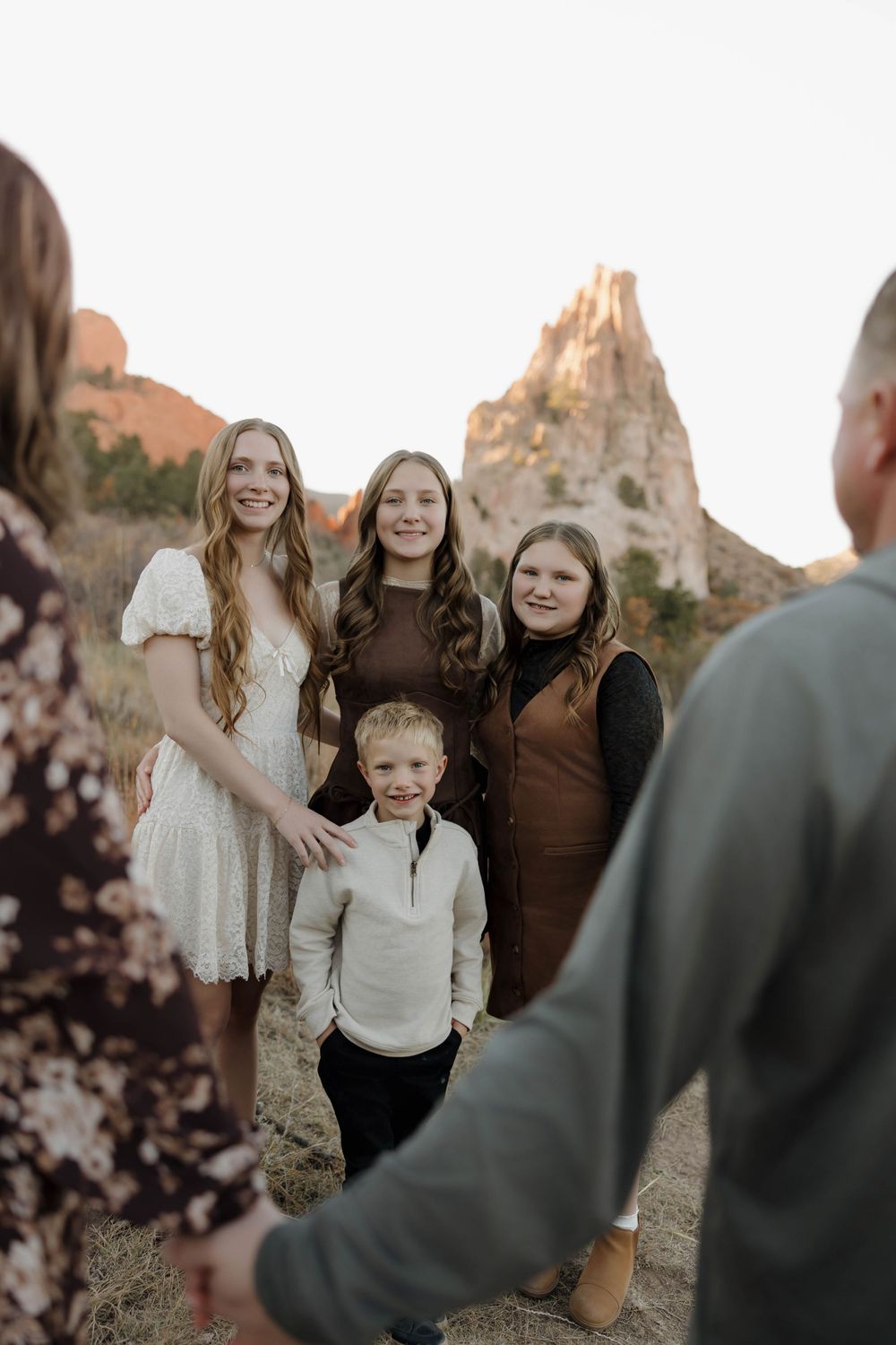 A group stands together outdoors against a backdrop of desert rock formations during golden hour.