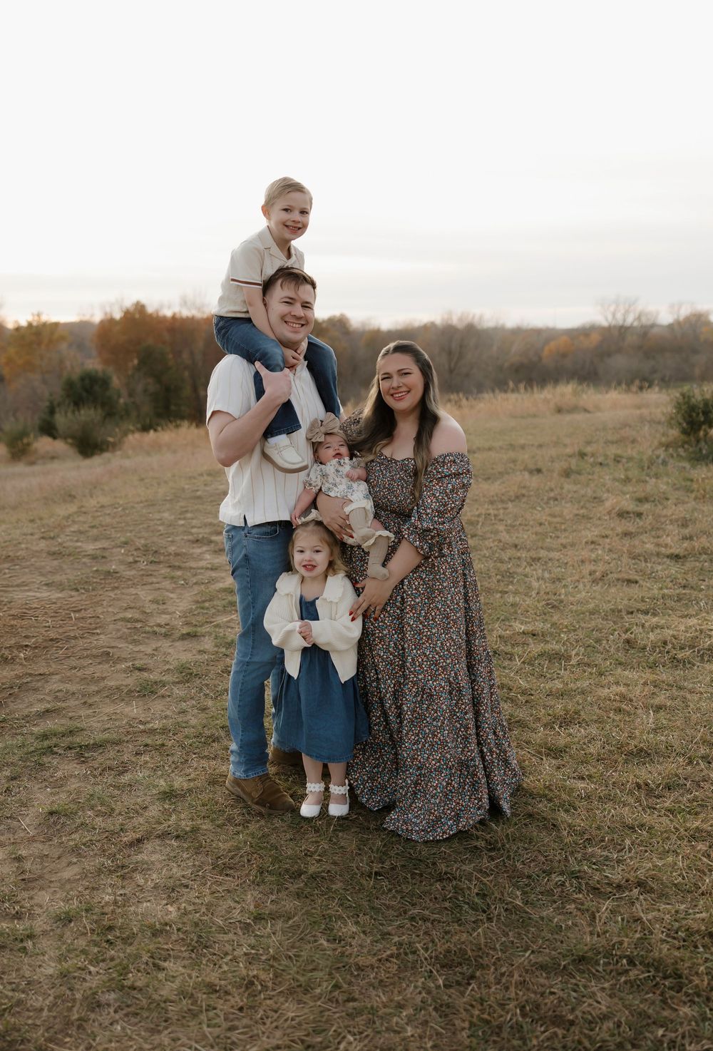 Family enjoying a tender moment together in a rustic field during golden hour.